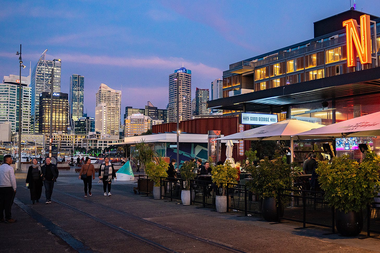 People stroll along the Wynyard Quarter waterfront at dusk.